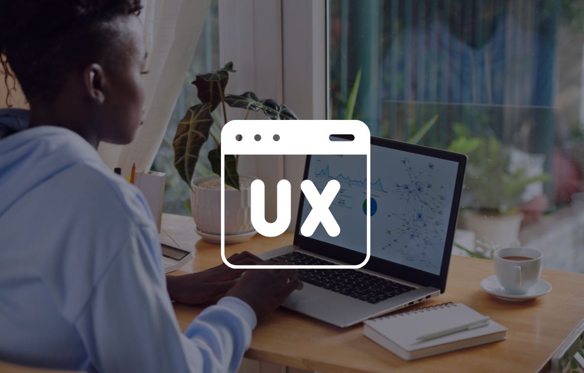 A person works on a laptop at a desk with charts on the screen; a large “UX” icon is overlaid on the image.