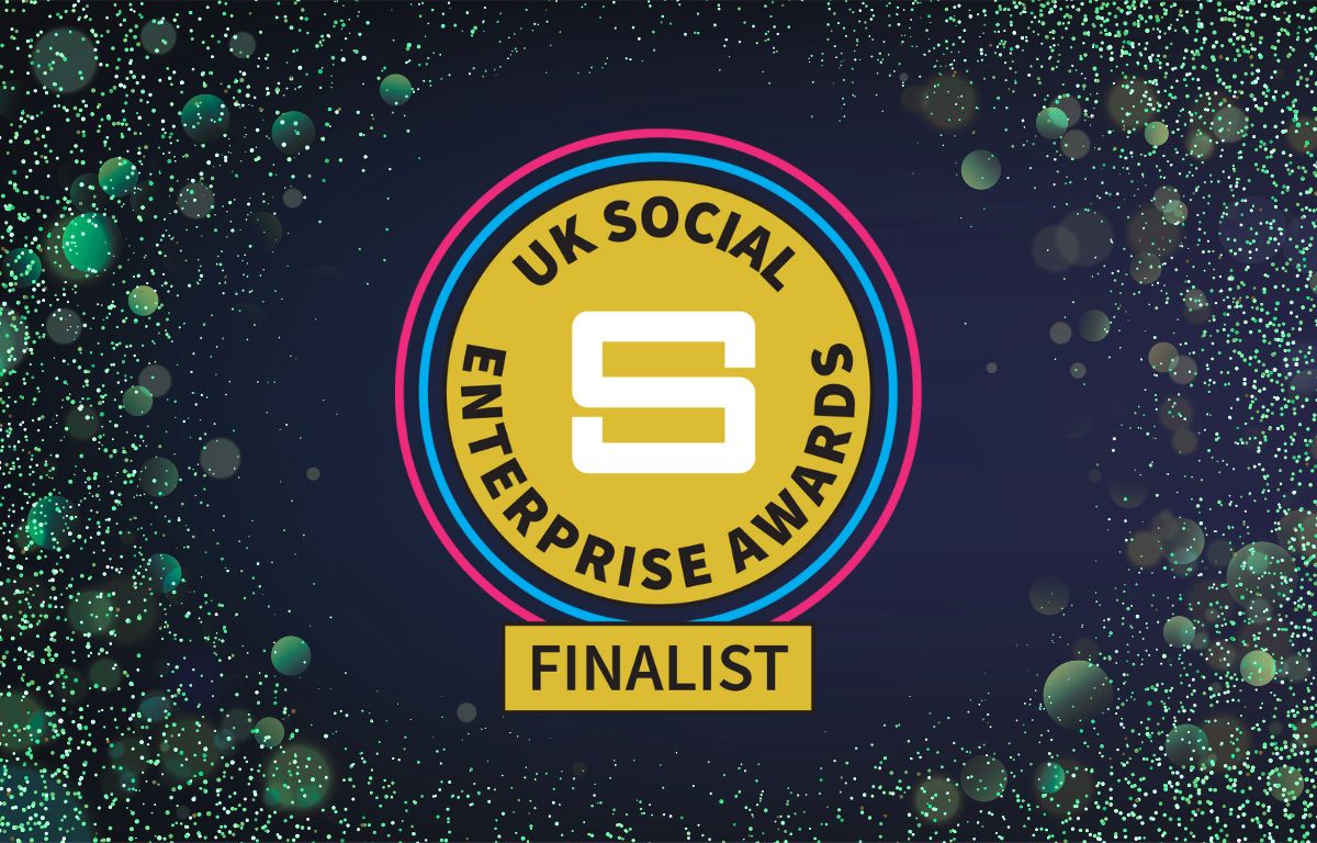 UK Social Enterprise Awards finalist badge with gold, pink, and blue circles, surrounded by green and blue confetti-like dots on a dark background celebrates social enterprise awards recognition.