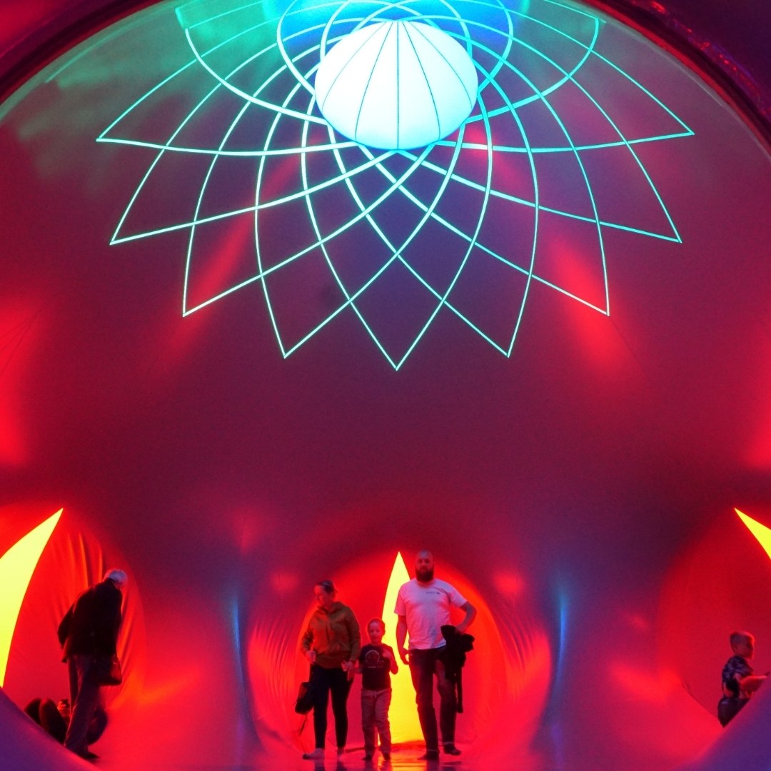 A woman speaks into a microphone on stage, flanked by others; handwritten signs are visible in the background. Designed by Circular Design, a not-for-profit web design agency.